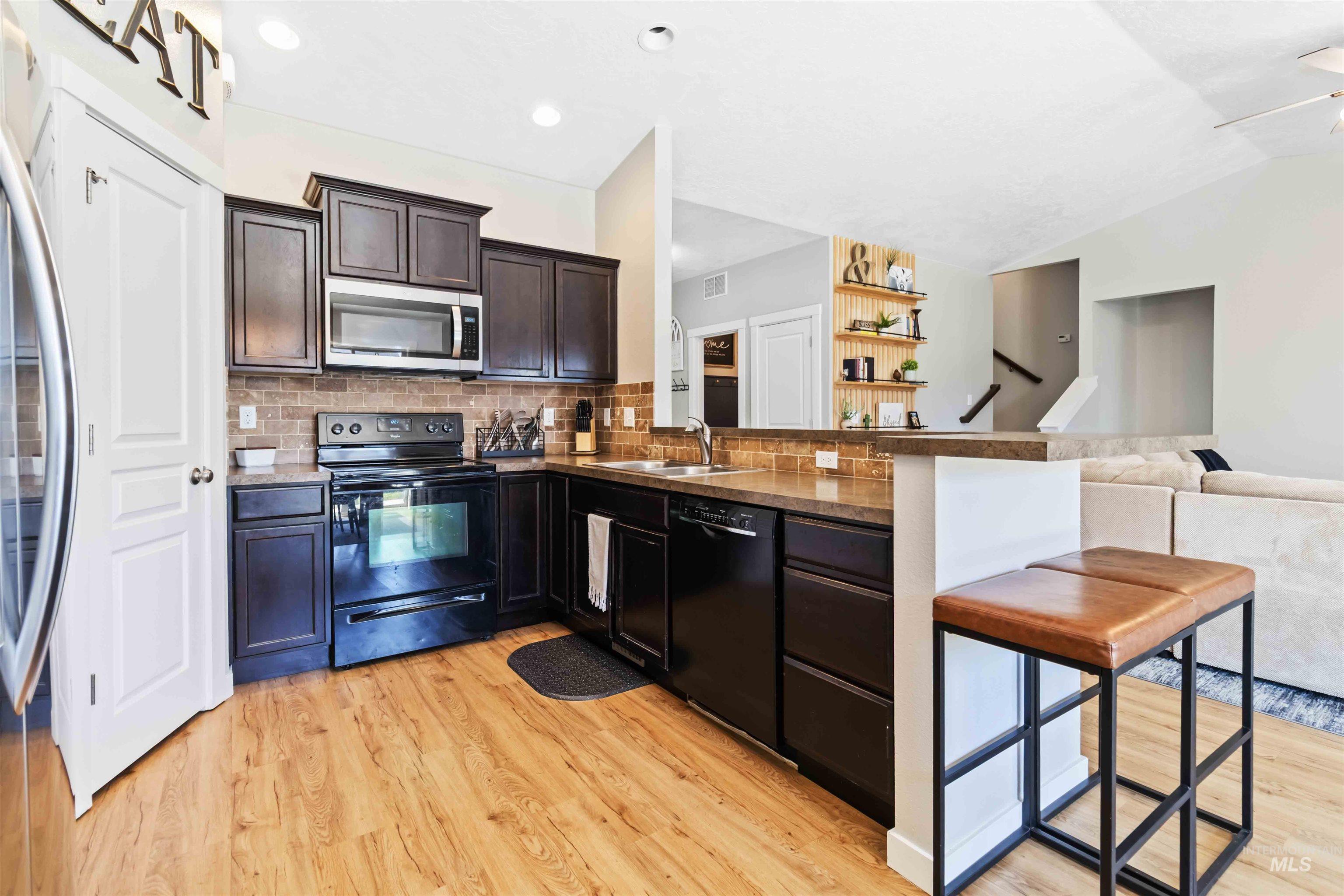 588 Gateway Avenue Middleton, ID 83644 - Photo 42 of 42 Kitchen featuring black appliances, open floor plan, light wood-type flooring, a peninsula, and backsplash