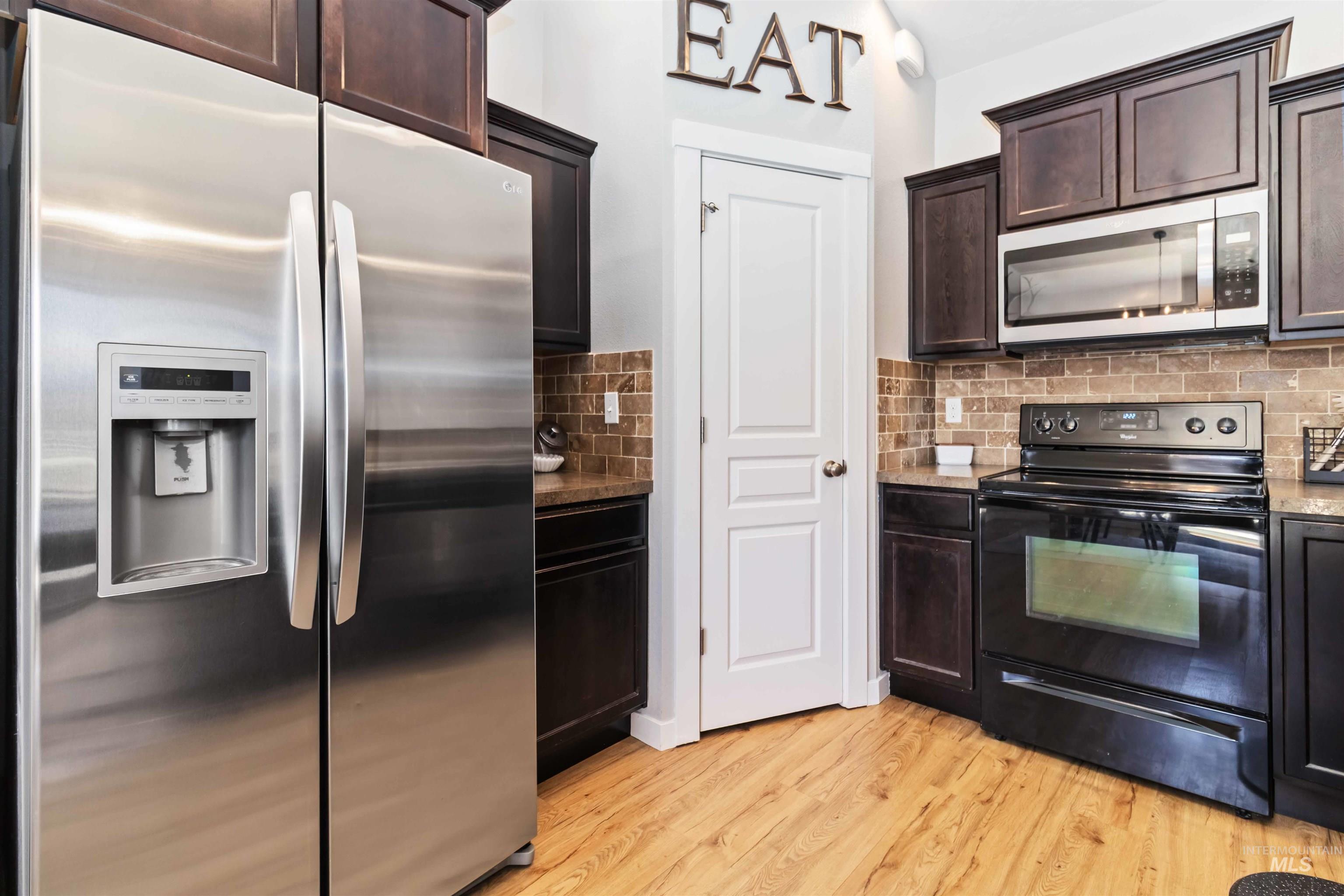 588 Gateway Avenue Middleton, ID 83644 - Photo 20 of 42 Kitchen with stainless steel appliances, dark wood finish cabinetry, light wood finished floors, and backsplash