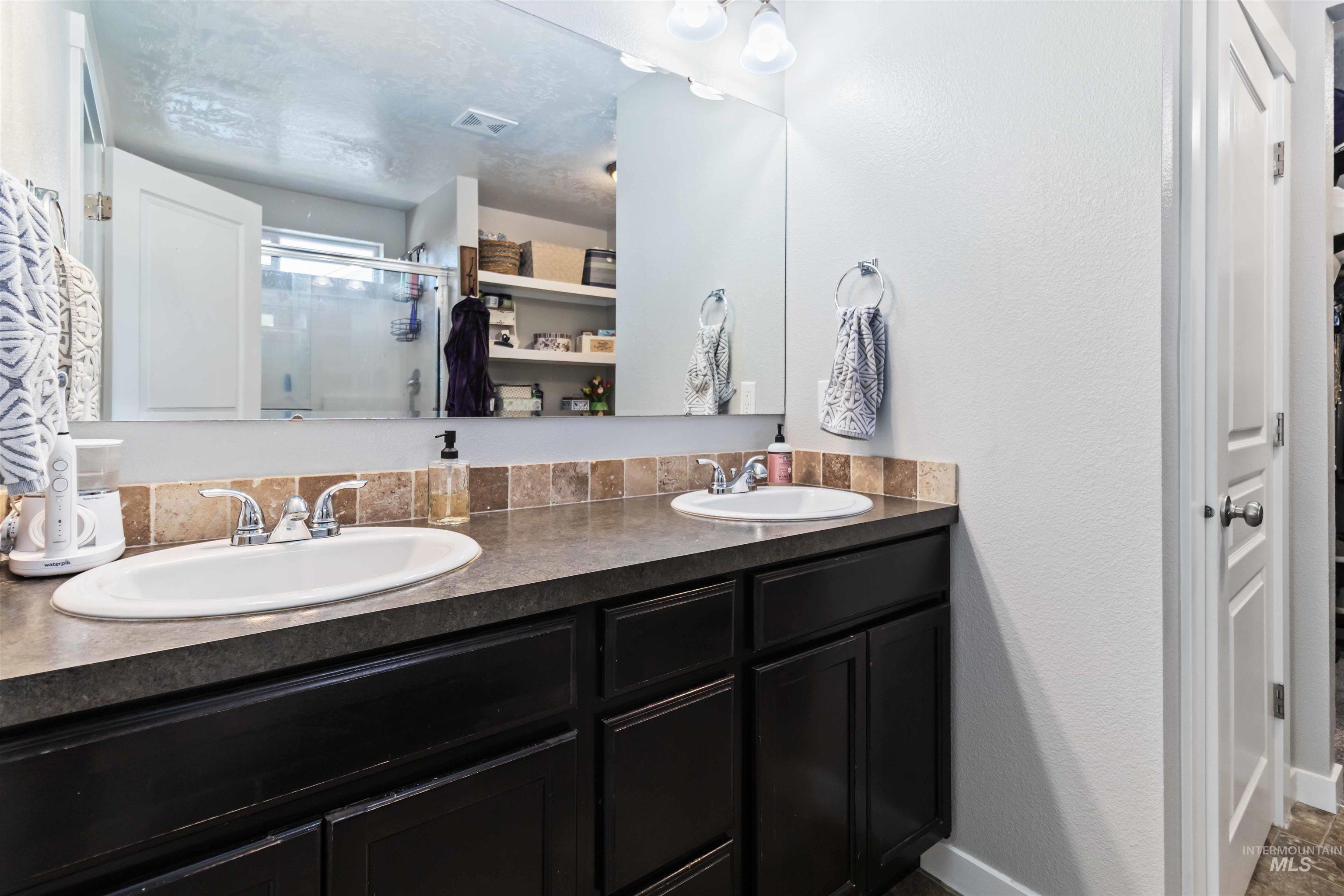 588 Gateway Avenue Middleton, ID 83644 - Photo 32 of 42 Bathroom with double vanity, a shower stall, a textured wall, and a walk in closet