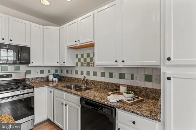 a kitchen with stainless steel appliances granite countertop a stove a sink and a white cabinets