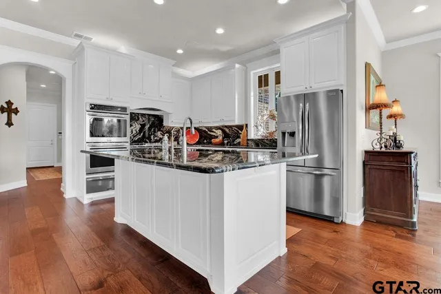 a kitchen with kitchen island white cabinets and stainless steel appliances