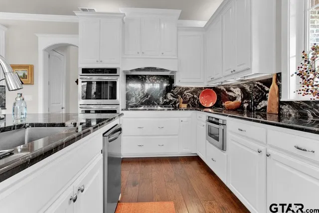a kitchen with stainless steel appliances granite countertop a sink a stove and cabinets