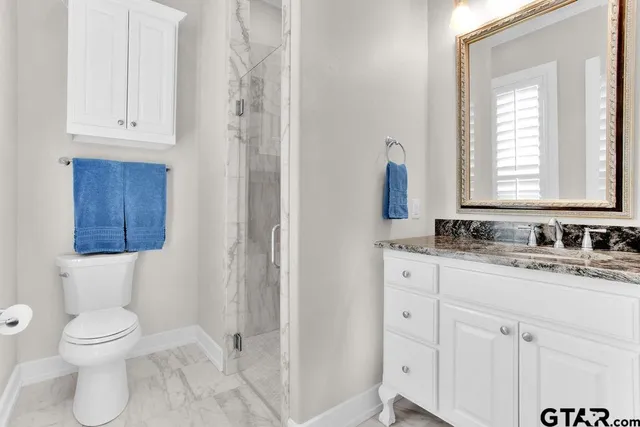 a bathroom with a granite countertop toilet sink and mirror