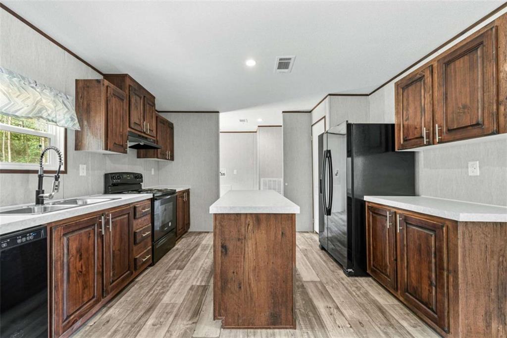 a kitchen with stainless steel appliances a sink cabinets and wooden floor