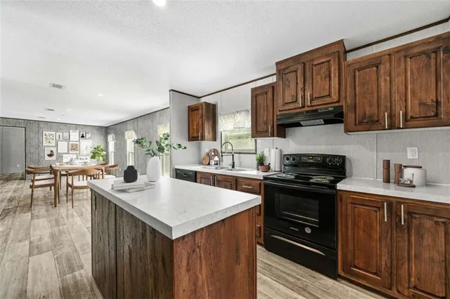 a kitchen with stainless steel appliances granite countertop a stove a sink dishwasher and a refrigerator with wooden cabinets