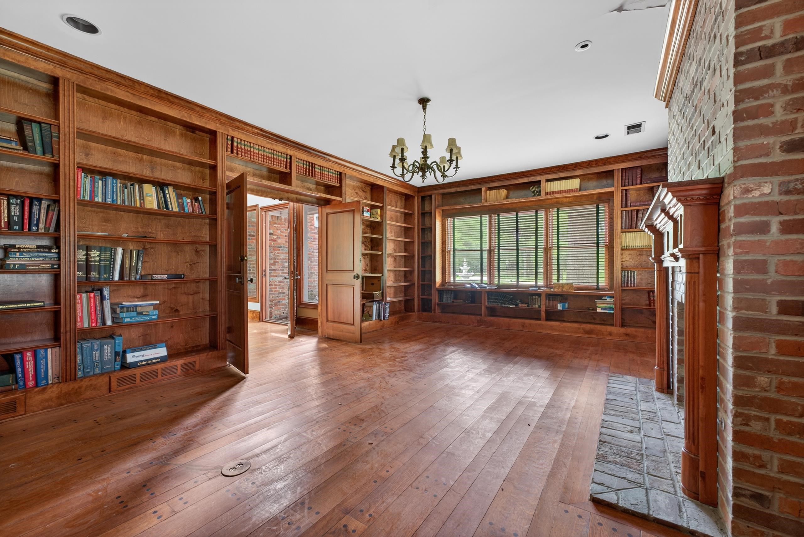 530 West Raines Road Memphis, TN 38109 - Photo 18 of 38 Room featuring extensive built-in wooden shelving, a brick fireplace, wood-finish flooring, and a large window with integrated shelving