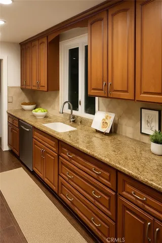 a kitchen with granite countertop wooden cabinets a sink and dishwasher