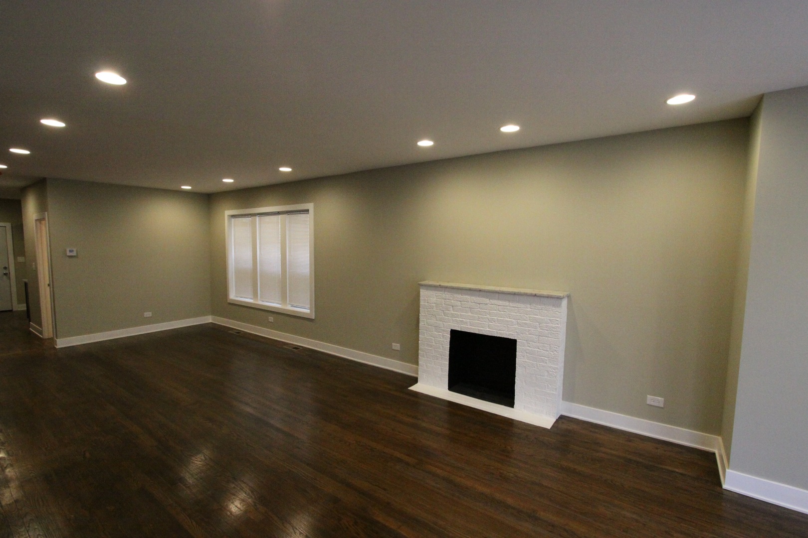 111 West 74th Street Chicago, IL 60621 - Photo 4 of 10 a view of an empty room with wooden floor and a fireplace