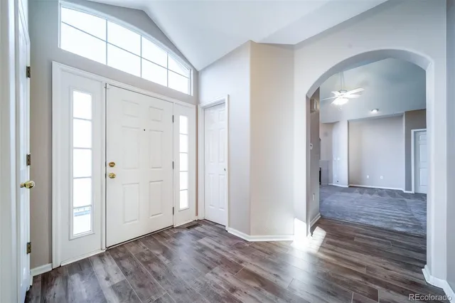 a view of an empty room with wooden floor and a mirror