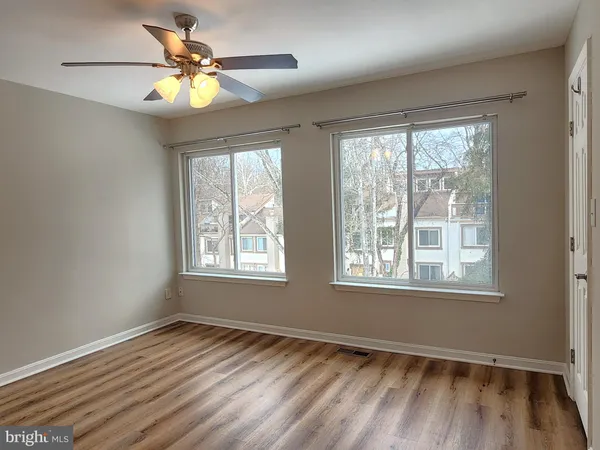 a view of an empty room with a window and wooden floor