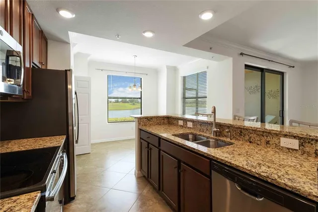 a kitchen with granite countertop stainless steel appliances a sink stove and refrigerator