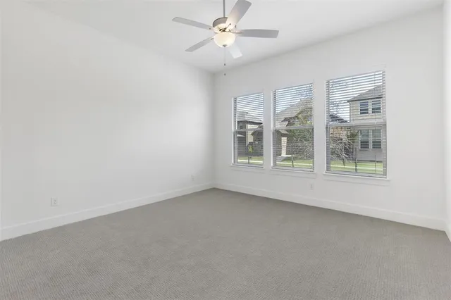 an empty room with windows and ceiling fan