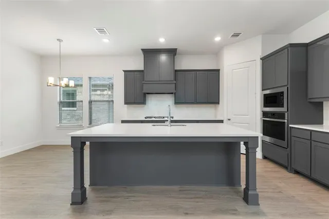 a kitchen with kitchen island stainless steel appliances a sink cabinets and wooden floor