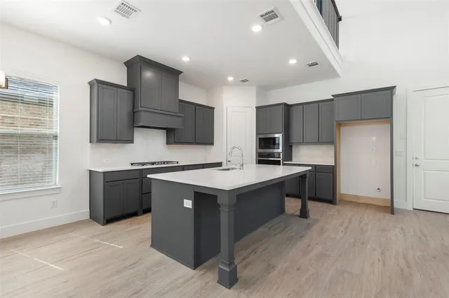 a kitchen with kitchen island stainless steel appliances a sink cabinets and wooden floor