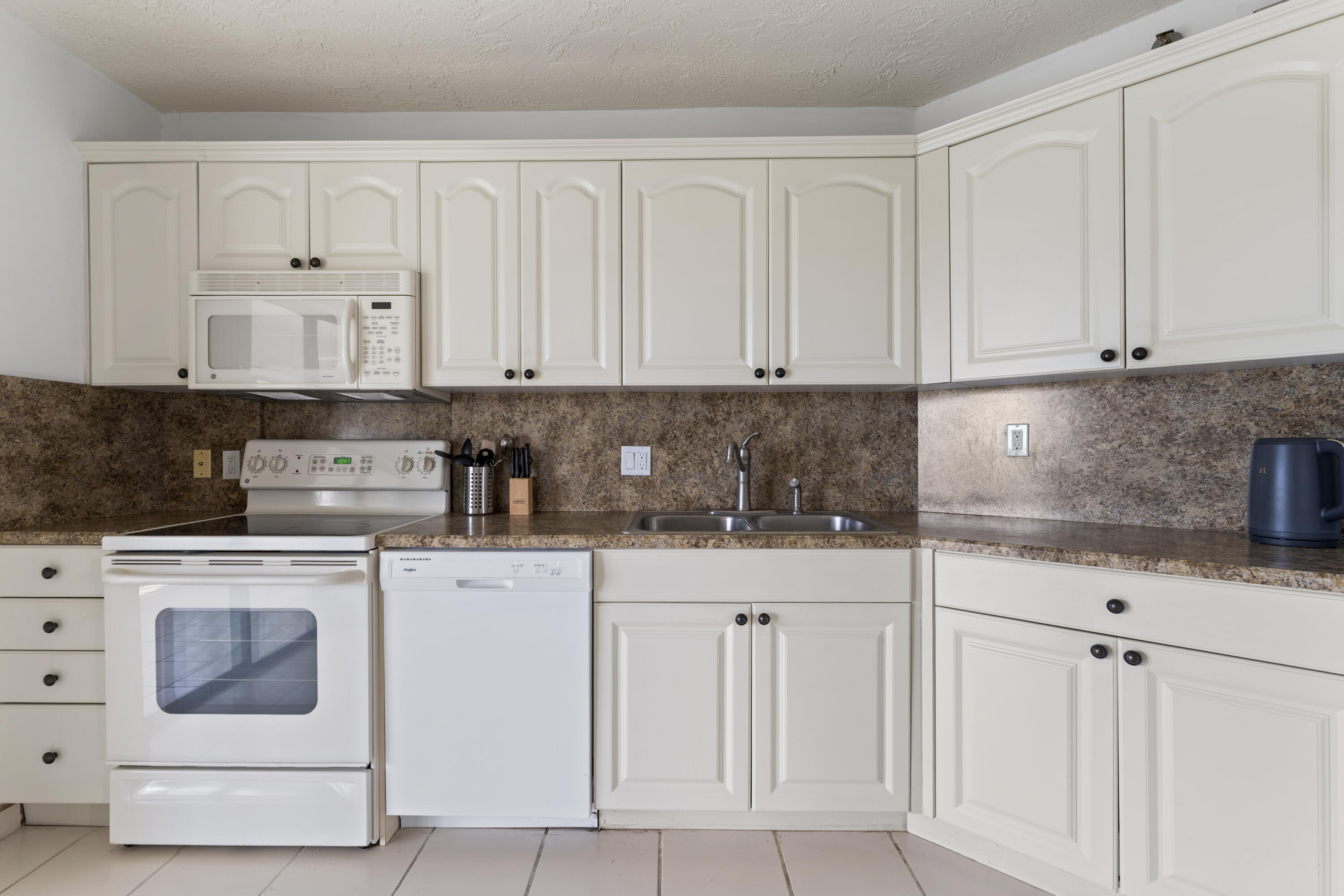 7507 La Paz Boulevard, Unit 407 Boca Raton, FL 33433 - Photo 11 of 31 a kitchen with white cabinets and white appliances