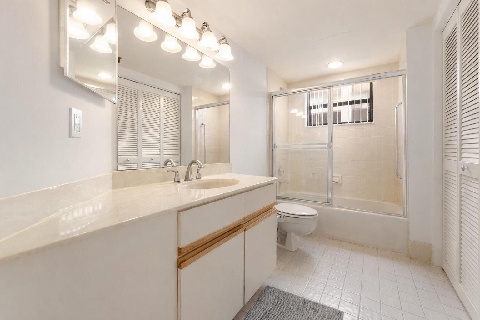 7507 La Paz Boulevard, Unit 407 Boca Raton, FL 33433 - Photo 19 of 31 a bathroom with a granite countertop sink a toilet a shower and a mirror