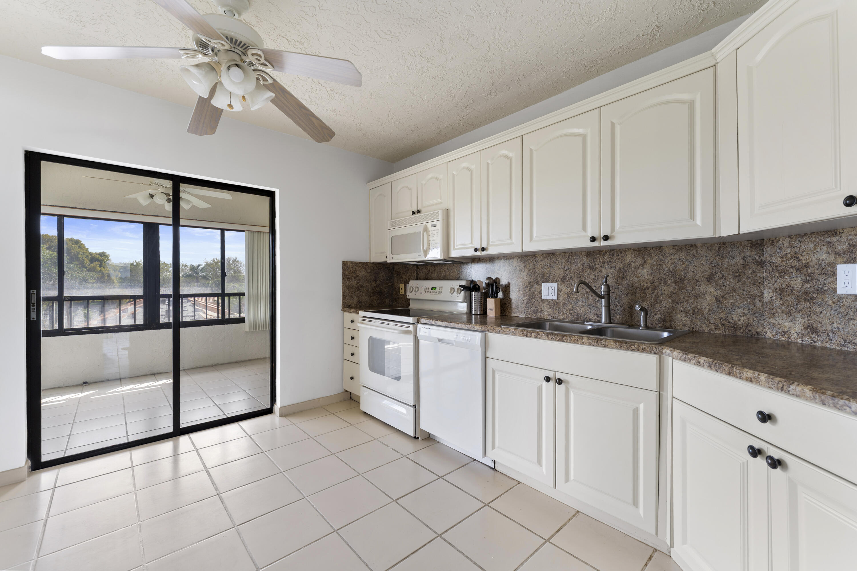 7507 La Paz Boulevard, Unit 407 Boca Raton, FL 33433 - Photo 9 of 31 a kitchen with granite countertop white cabinets and white appliances