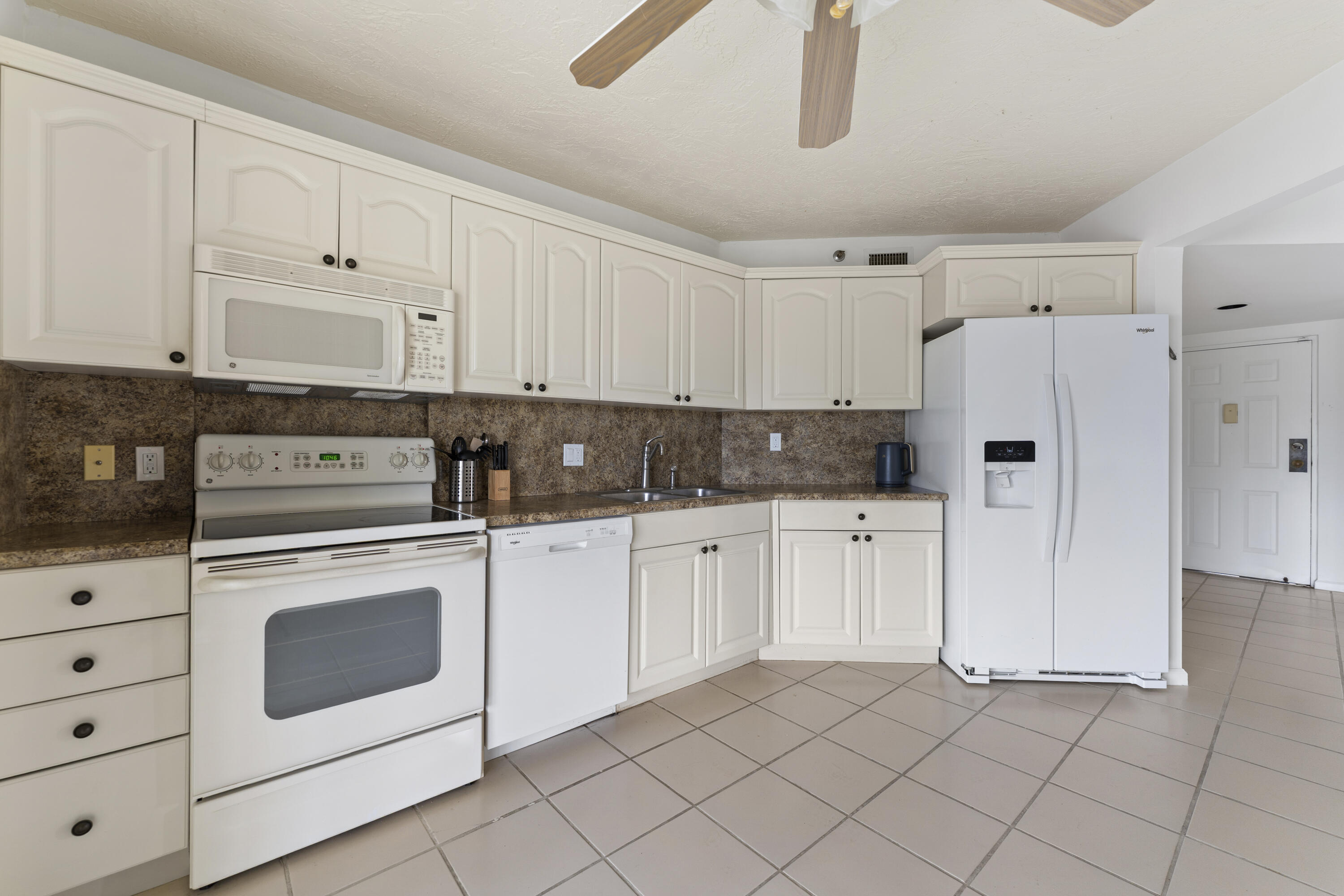 7507 La Paz Boulevard, Unit 407 Boca Raton, FL 33433 - Photo 10 of 31 a kitchen with white cabinets and white appliances
