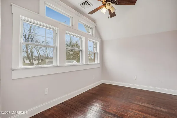 an empty room with wooden floor a ceiling fan and a window