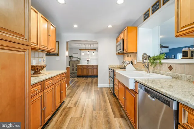 a kitchen with stainless steel appliances granite countertop a sink and wooden cabinets