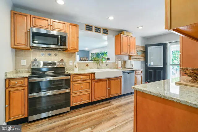 a kitchen with stainless steel appliances granite countertop wooden cabinets and a stove top oven
