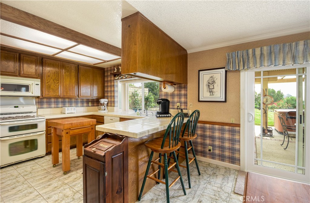 871 Kevin Corona, CA 92878 - Photo 11 of 34 a kitchen with stainless steel appliances kitchen island granite countertop a table chairs and a refrigerator