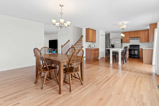 a dining room with wooden floor a chandelier a wooden table and chairs