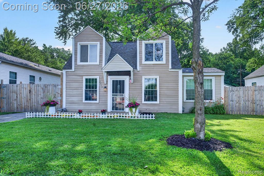 Two-story home with a dormer facade, light-colored horizontal siding, and a dark shingle roof