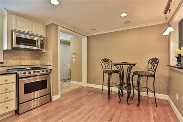 2648 Massachusetts Avenue Lexington, MA 02421 - Photo 6 of 19 a kitchen with stainless steel appliances a stove a microwave a dining table and chairs with wooden floor