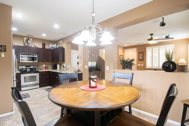 a kitchen with stainless steel appliances kitchen island granite countertop a sink a stove a dining table and chairs