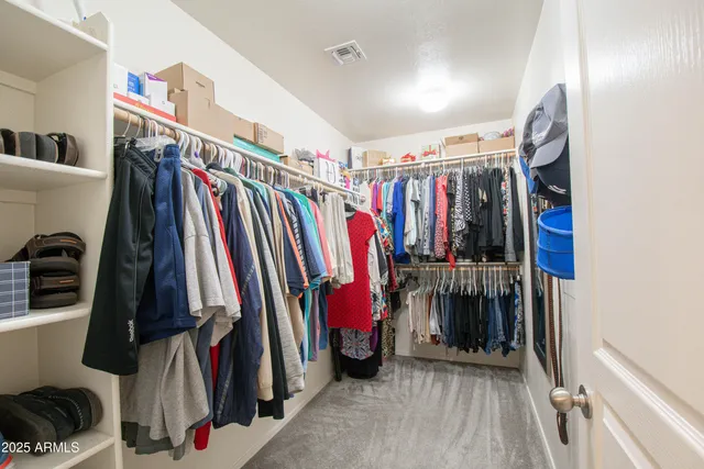 a view of walk in closet with clothes and shoes