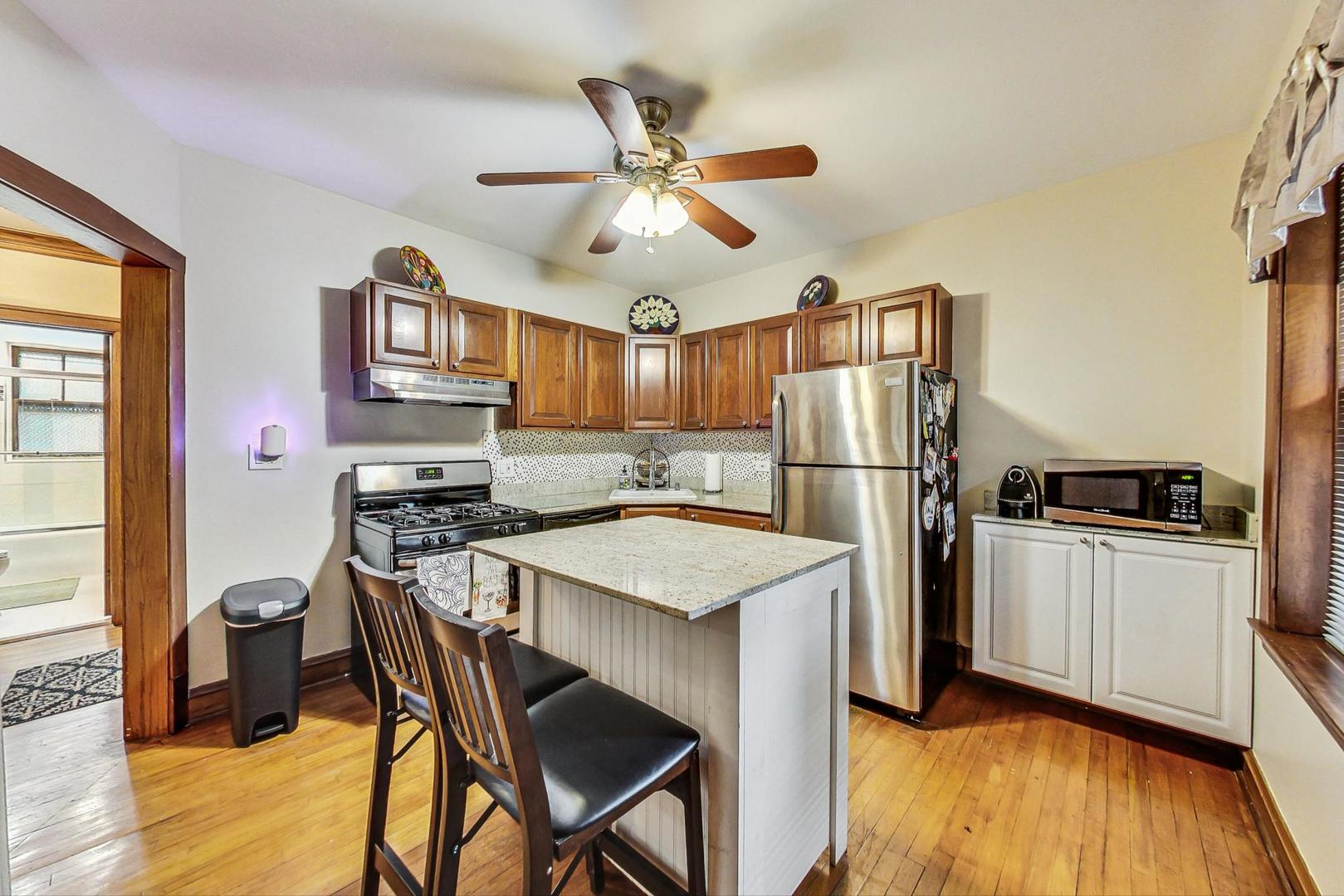 2004 West Walton Street, Unit 2B Chicago, IL 60622 - Photo 7 of 17 a kitchen with stainless steel appliances granite countertop a refrigerator a stove a sink dishwasher and a dining table with wooden floor