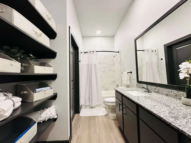 a bathroom with a granite countertop sink a toilet and shower