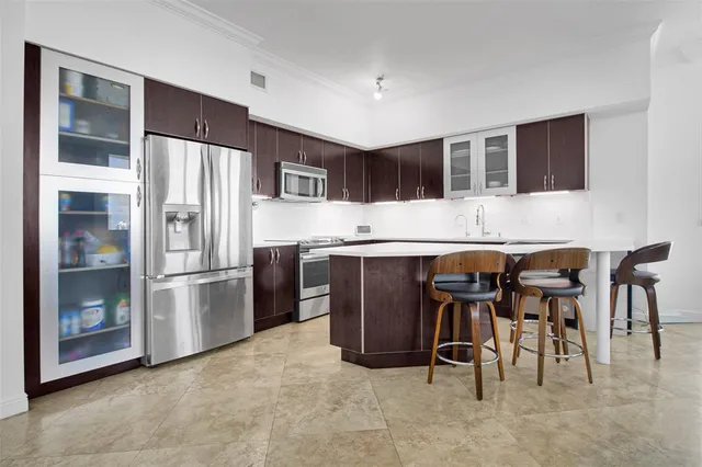 a kitchen with stainless steel appliances kitchen island granite countertop a refrigerator and a stove top oven