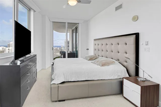 a bedroom with a bed and a flat tv screen on dresser