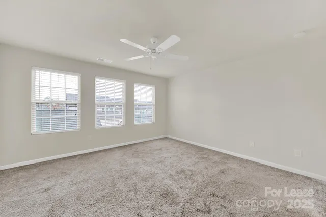 an empty room with a window and a ceiling fan