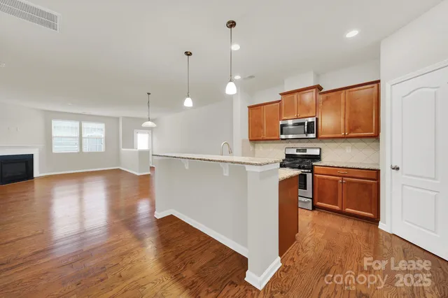 a kitchen with stainless steel appliances wooden floors wooden cabinets a refrigerator and a sink