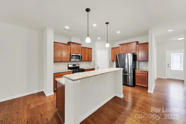 a kitchen with stainless steel appliances granite countertop a refrigerator a stove top oven a sink dishwasher and a refrigerator