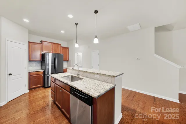 a kitchen with stainless steel appliances granite countertop a sink a refrigerator and a stove