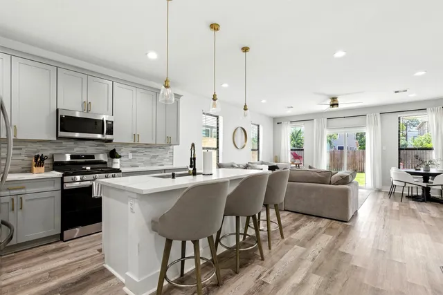 a kitchen with stainless steel appliances granite countertop a stove top oven a sink dishwasher a dining table and chairs with wooden floor