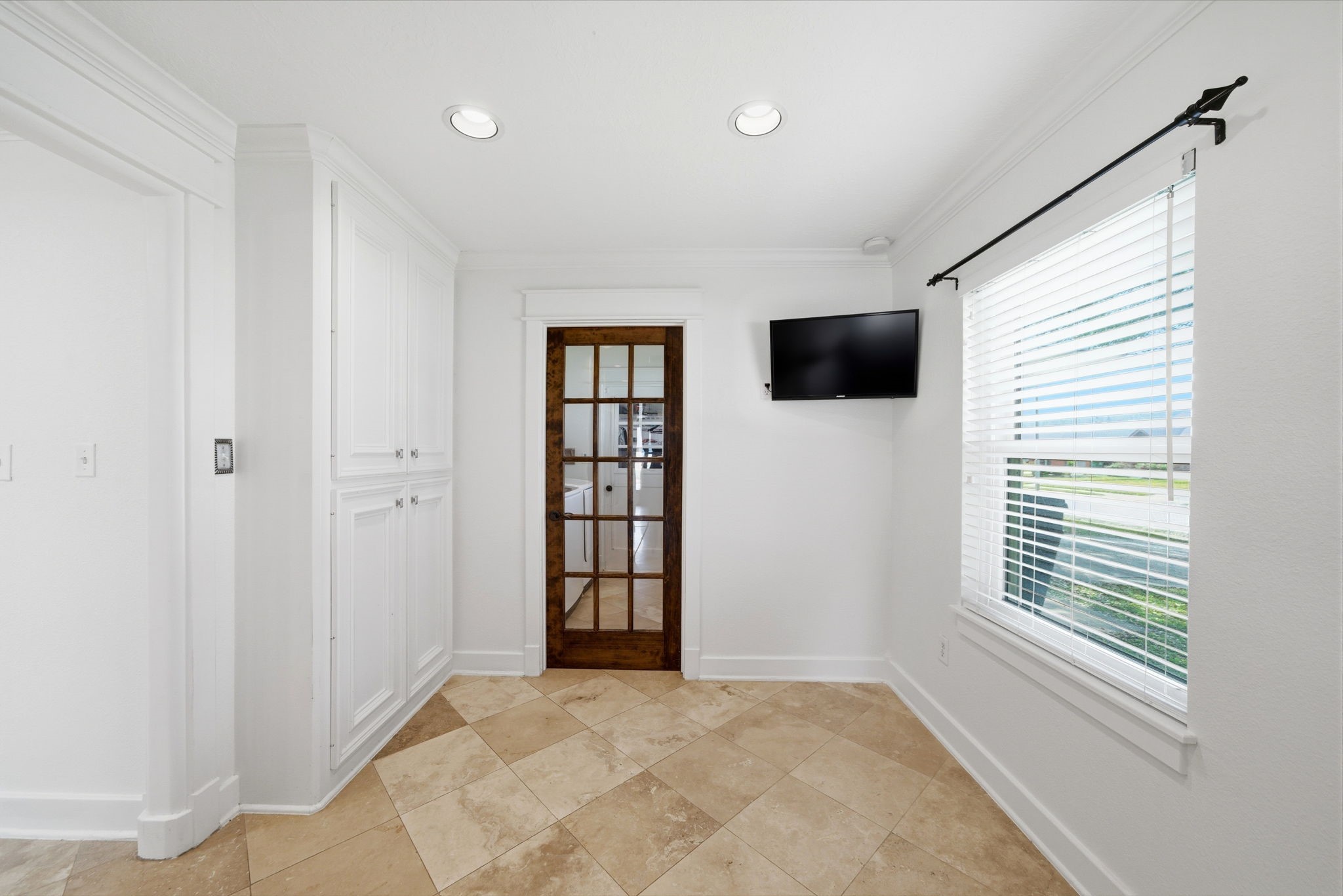 6427 Waltway Drive Houston, TX 77008 - Photo 11 of 37 Breakfast area has built-in cabinetry for storage and a wall-mounted TV. A wooden-framed glass door adds a touch of elegance, leading to the utility room.