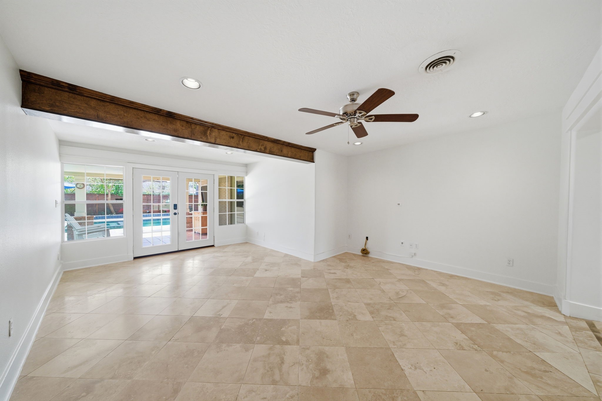 6427 Waltway Drive Houston, TX 77008 - Photo 14 of 37 Bright and spacious den with travertine flooring, a ceiling fan, and recessed lighting. French doors lead to a backyard with a pool, enhancing indoor-outdoor living.