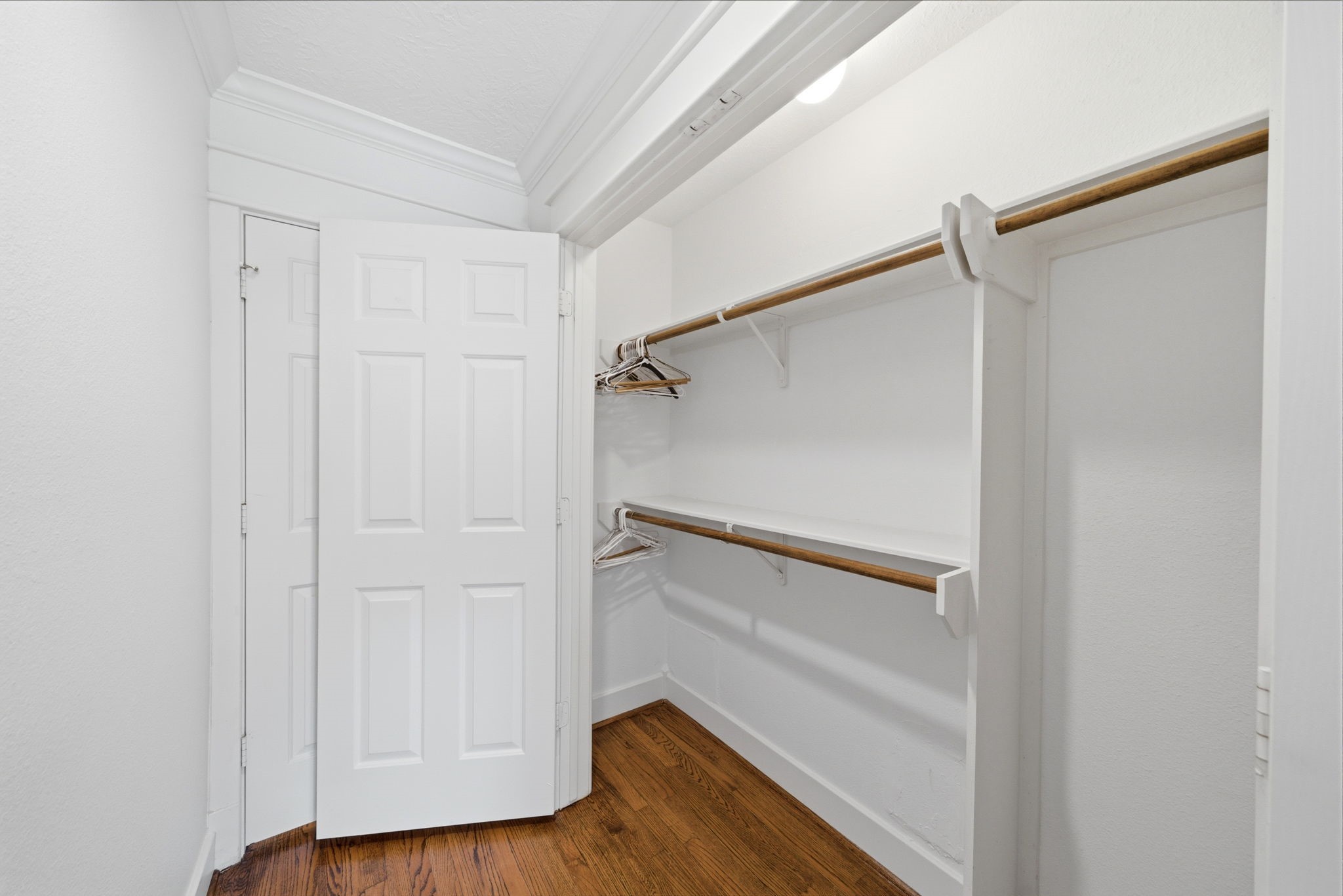 6427 Waltway Drive Houston, TX 77008 - Photo 24 of 37 This photo shows a spacious primary closet with white walls, wooden rods, and shelves for ample storage. Perfect for organizing clothes and accessories.