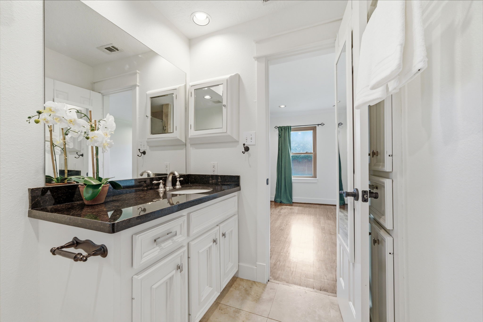 6427 Waltway Drive Houston, TX 77008 - Photo 25 of 37 This bathroom features a sleek design with a large mirror, granite countertop, and modern fixtures. It includes a glass-enclosed shower, neutral tile flooring, and ample natural light.