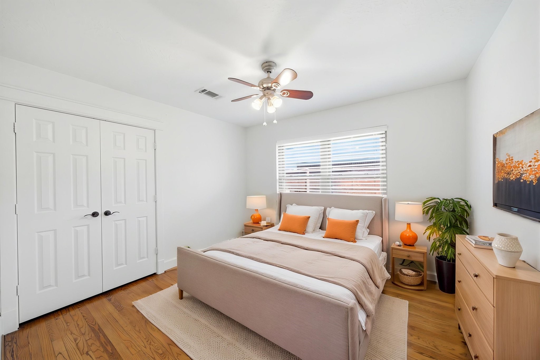6427 Waltway Drive Houston, TX 77008 - Photo 27 of 37 *AI staging* This bright bedroom features hardwood flooring and ample natural light from a large window. It includes a ceiling fan, double closet creating a warm and inviting space.