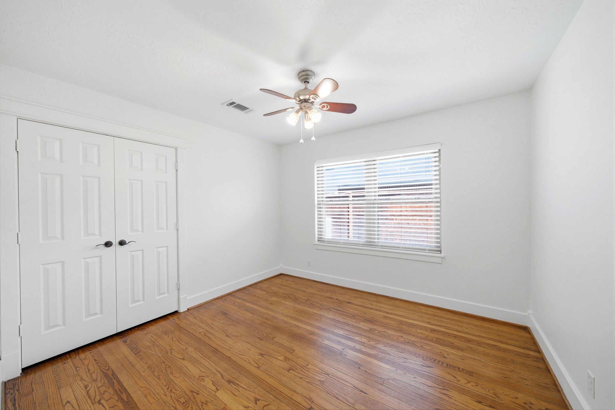 6427 Waltway Drive Houston, TX 77008 - Photo 28 of 37 This bright room features hardwood floors, a ceiling fan, and a large window with blinds for natural light. It includes a double-door closet, offering ample storage space.