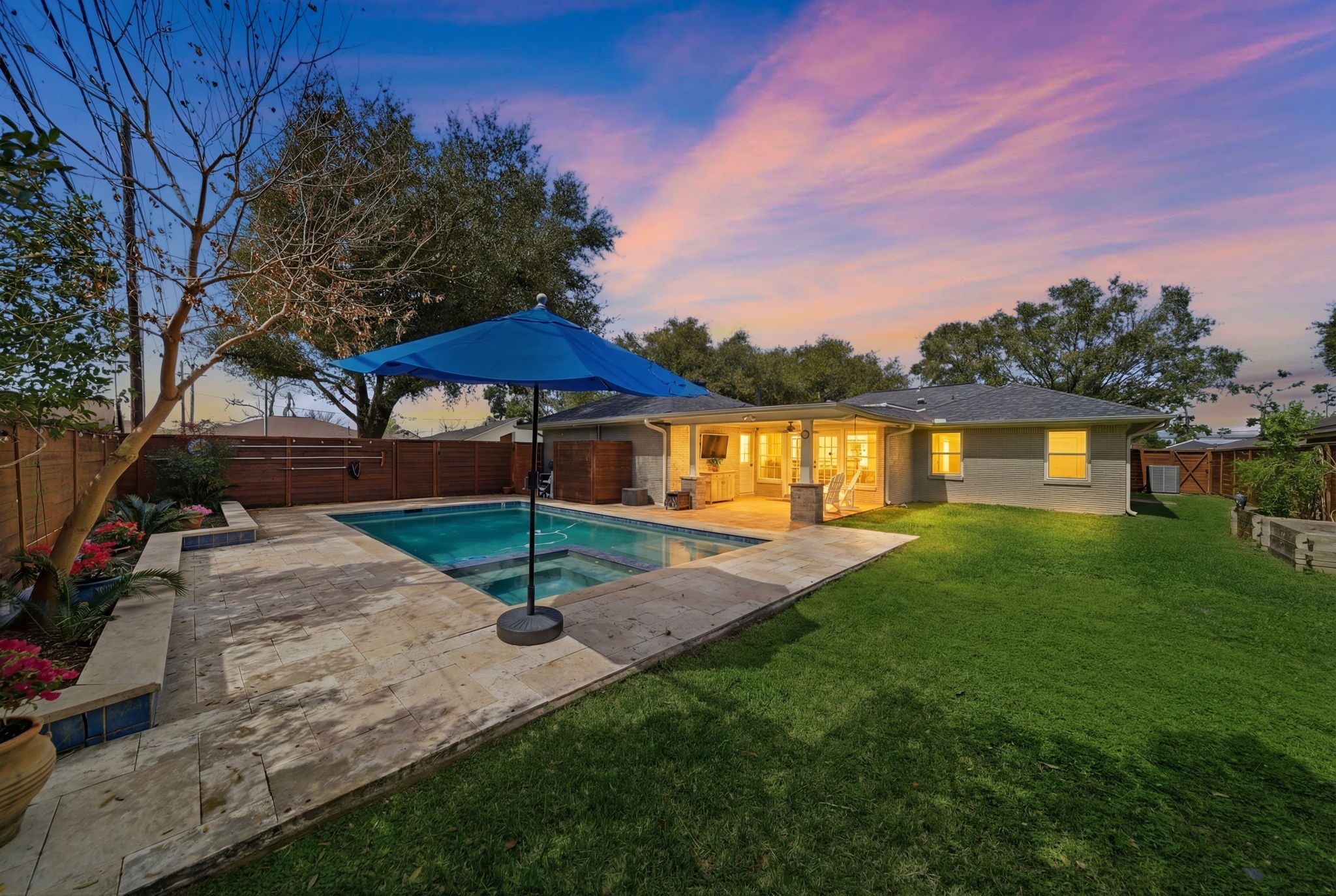 6427 Waltway Drive Houston, TX 77008 - Photo 37 of 37 This inviting backyard features a well-maintained pool with a spacious stone patio and walkway. The home has a covered patio area with warm lighting, perfect for outdoor gatherings, surrounded by lush greenery and privacy fencing.