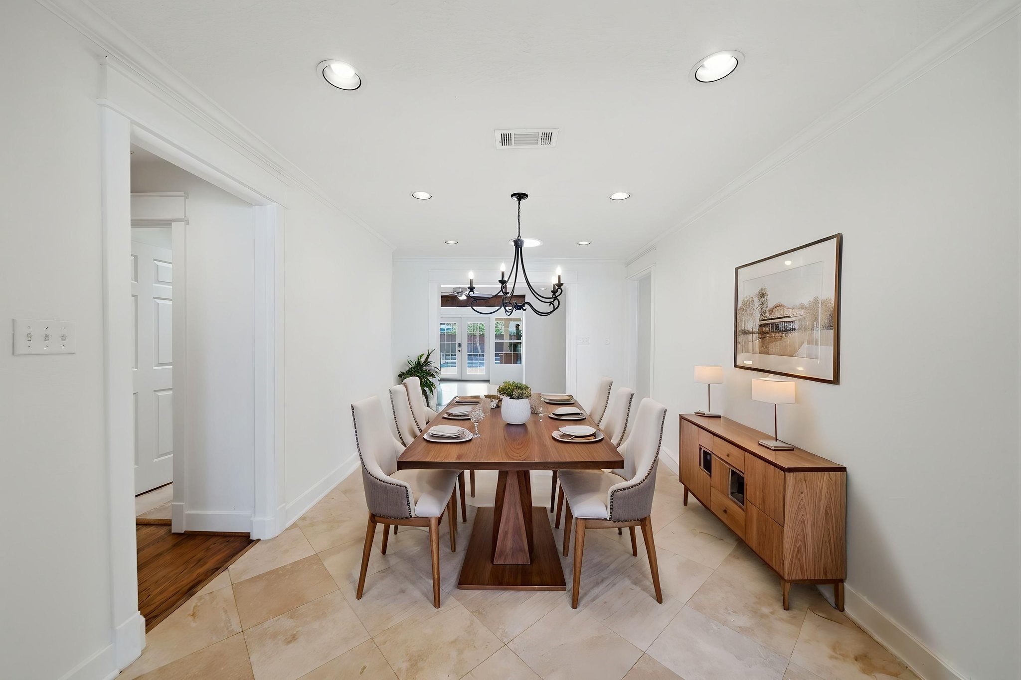 6427 Waltway Drive Houston, TX 77008 - Photo 6 of 37 *AI staging* Elegant yet casual dining room with a long wooden table set for six with a classic chandelier. The room with light-color travertine flooring connects to the living room, den and kitchen.