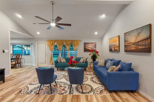 a living room with furniture a chandelier and a dining table with wooden floor