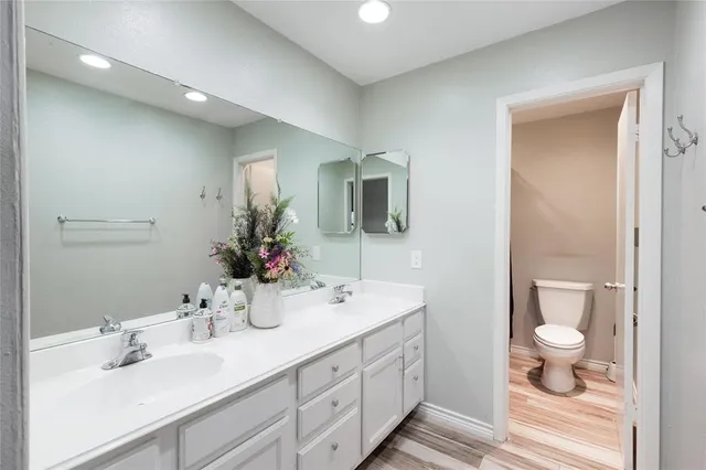 a bathroom with a double vanity sink toilet and mirror